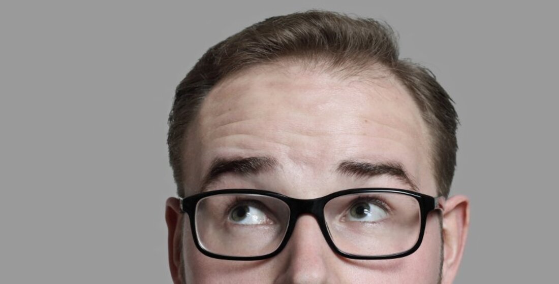 Mann mit Brille blickt skeptisch nach oben